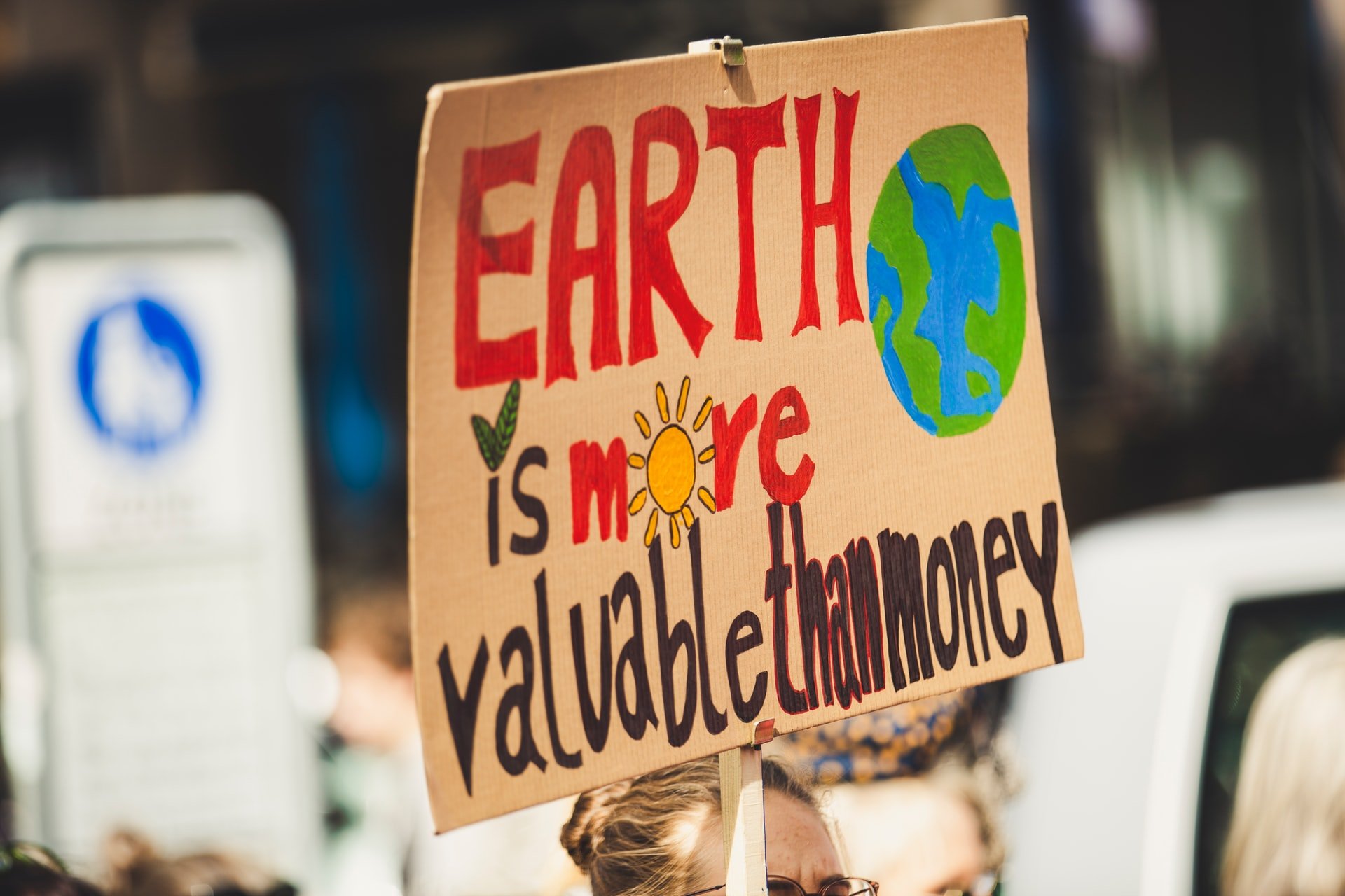 A protester holding a sign that reads 'Earth is more valuable than money'.