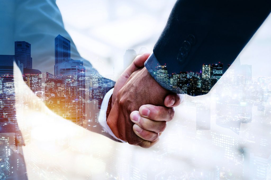 Two people shaking hands illustrating a partnership between Visa and Coinbase to enable instant transactions for crypto users as part of an ongoing effort to make integration between traditional finance and blockchain technologies more seamless, including the launch of a debit card earlier this year.